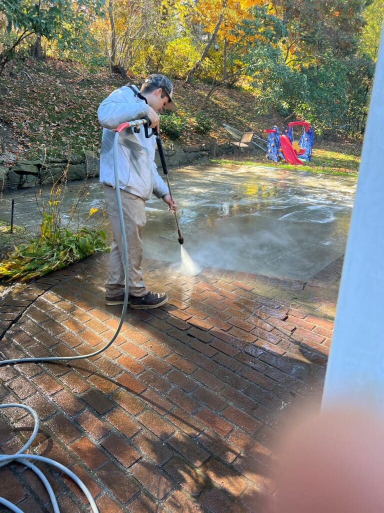 "Professional pressure washing technician safely cleaning vinyl siding in Nassau County using soft wash techniques and proper PSI settings"