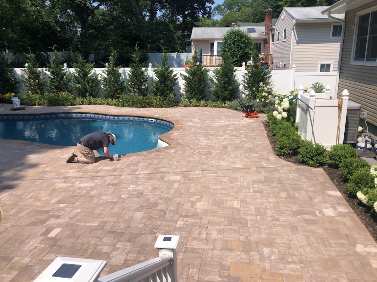 Matthew applying paver sealer by hand along pool coping edge during restoration — Pressure Wash Long Island, Nassau County