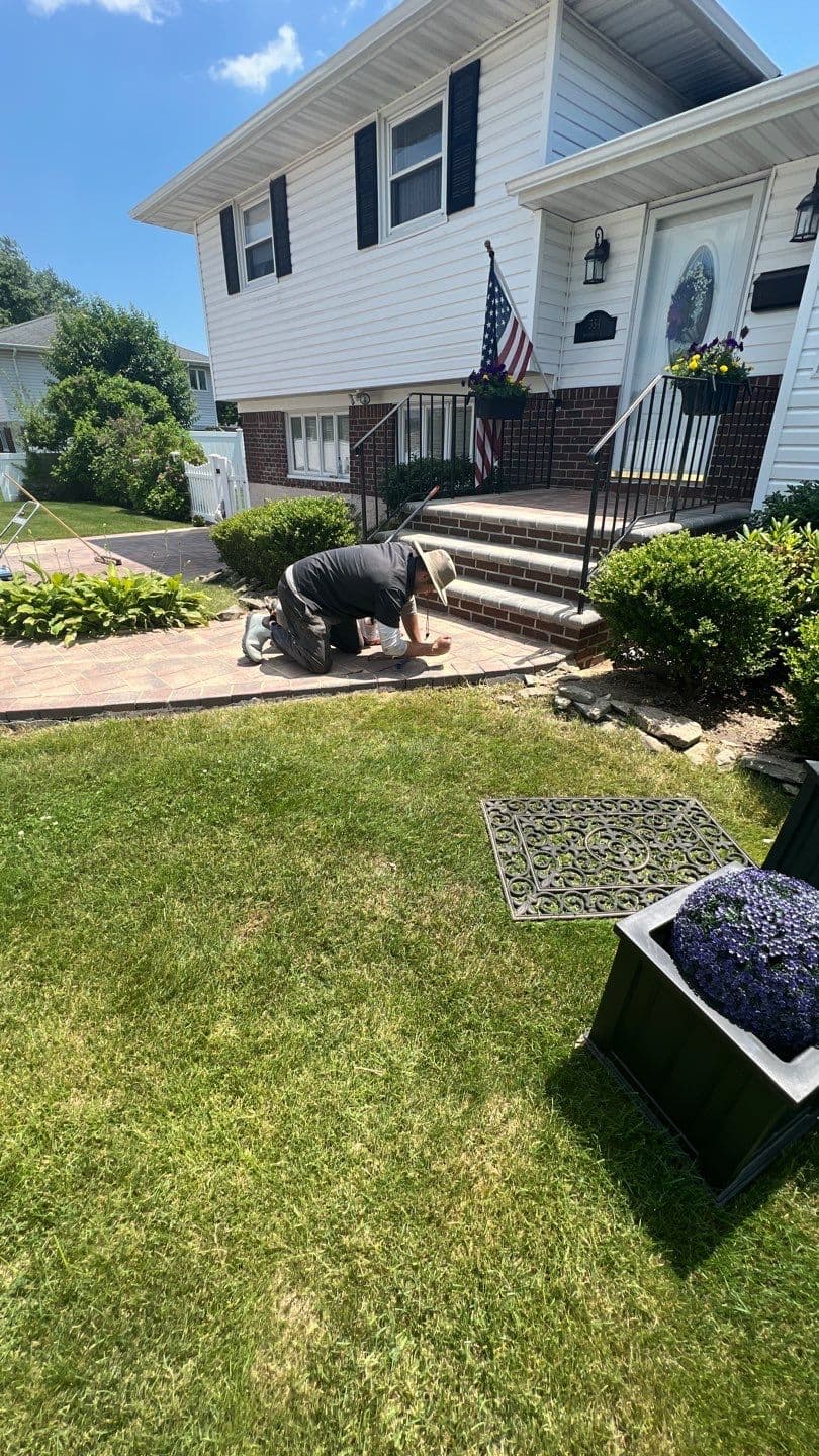 Matthew hand detailing paver soldier course border on a residential front walkway — paver sand restoration by Pressure Wash Long Island, Bethpage NY