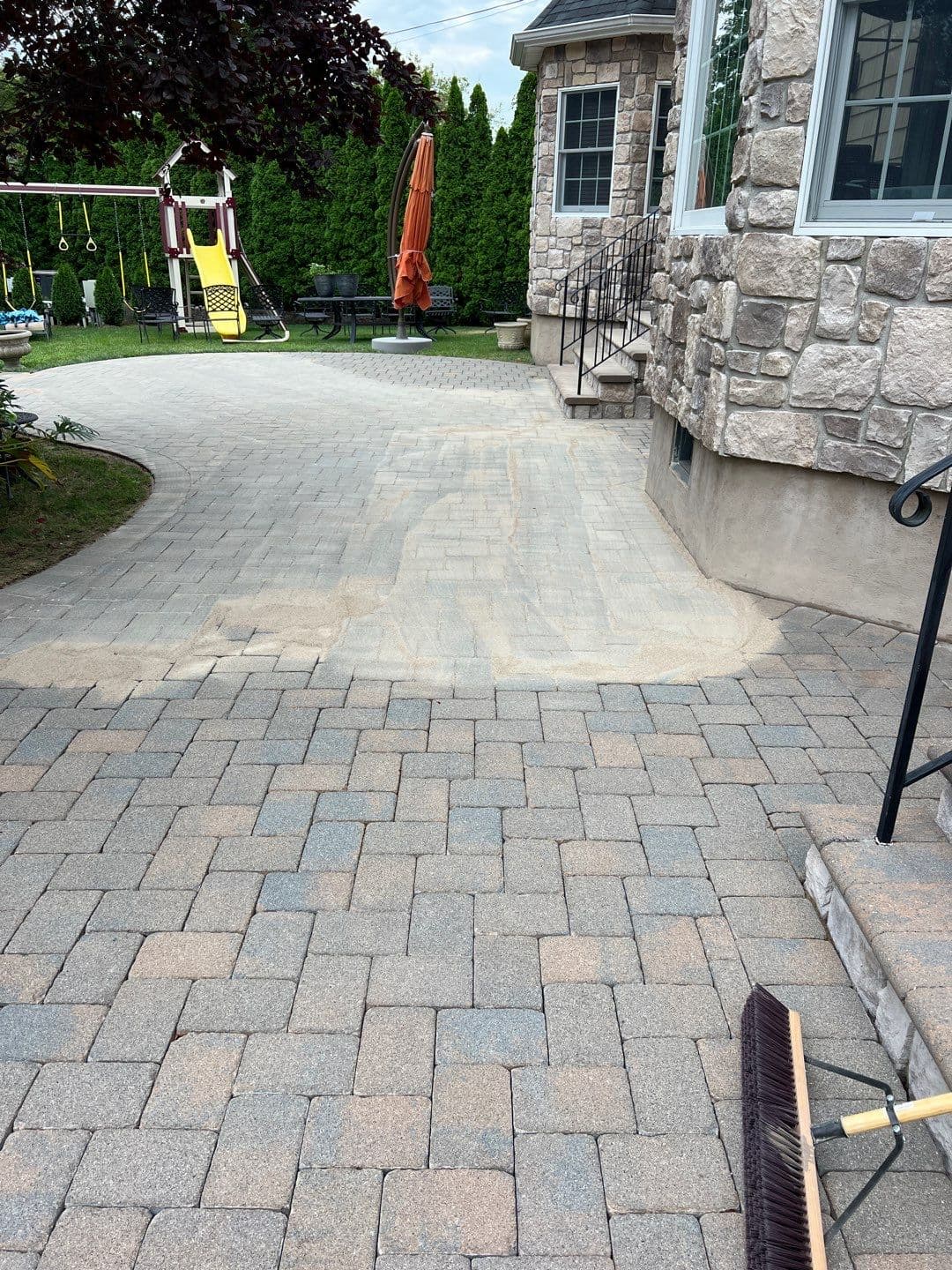 Fresh sand swept into paver joints mid-restoration on a Merrick NY paver driveway — Pressure Wash Long Island