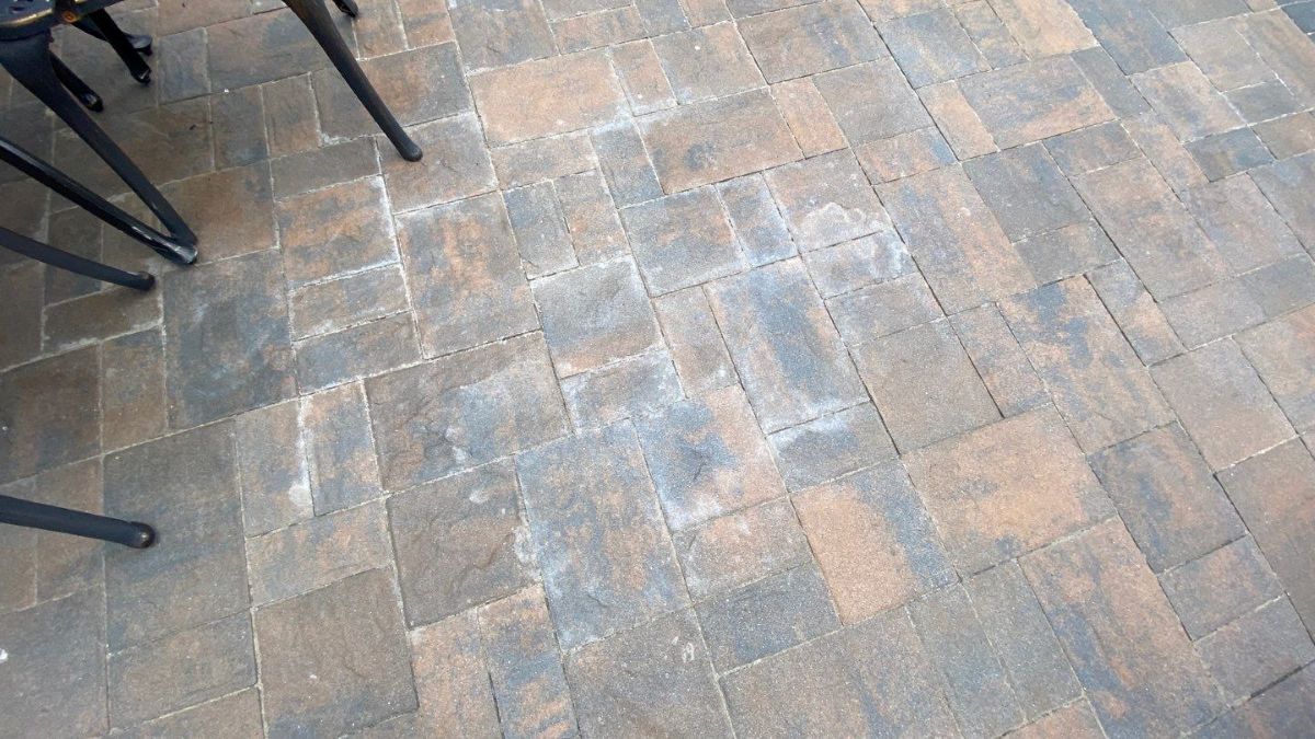 White haze and cloudy sealer film on a concrete paver patio — failed paver sealer caused by moisture trapped under coating — Nassau County Long Island